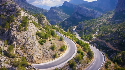 Winding road through a mountain pass with lush green vegetation and clear blue sky.