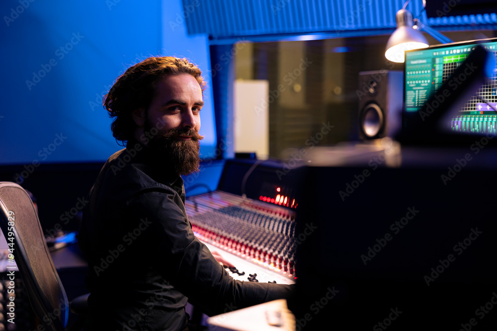 Portrait of sound designer working with mixing console and daw software on pc in professional studio, producing tracks for a pop album. Talented producer editing new music in control room. Portrait of sound designer working with mixing console and daw software on pc in professional studio, producing tracks for a pop album. Talented producer editing new music in control room.