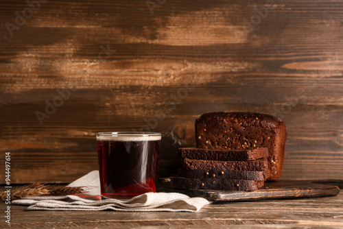 Glass of fresh kvass and slices of bread on wooden background photo