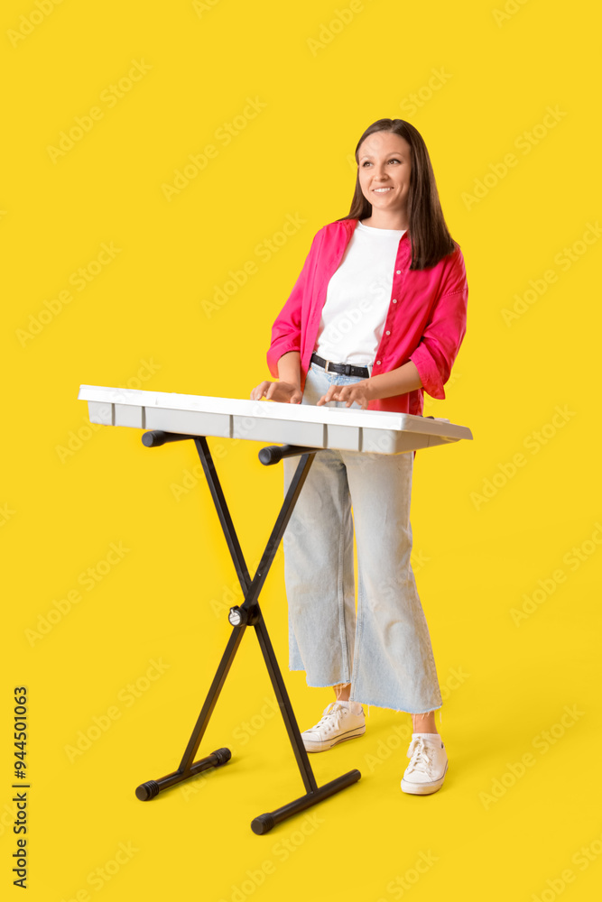 Young woman playing synthesizer on yellow background Young woman playing synthesizer on yellow background