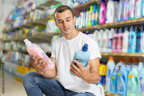 Man carefully selects cleaning product in industrial section of a supermarket