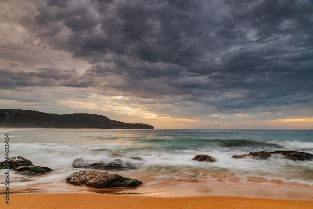 Sunrise at the seaside with rocks and beautiful diffused light by the rain clouds Sunrise at the seaside with rocks and beautiful diffused light by the rain clouds