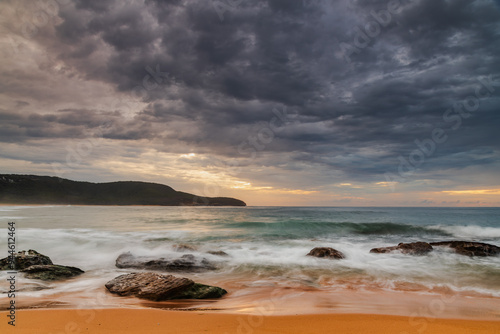 Sunrise at the seaside with rocks and beautiful diffused light by the rain clouds