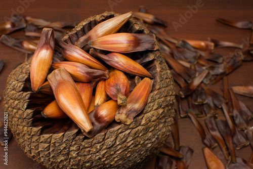Close pine cone on a wood background. The true fruit of Araucaria and its seeds are pine nuts.