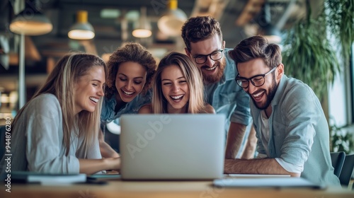 Group of friends gathered around a laptop, sharing laughs during a casual meeting in a modern workspace setting