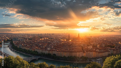 Stunning sunset over a sprawling cityscape with river views and dramatic clouds in Lyon, France during the golden hour