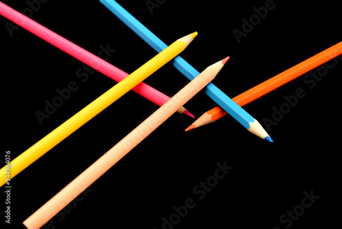 Several colored pencils lie on top of each other on a black background.