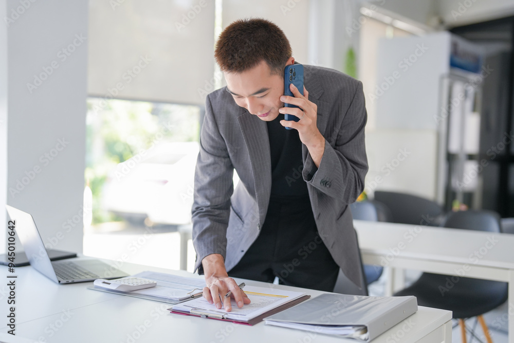Handsome confident asian secretary man clever smart professional businessman talking on phone in office Handsome confident asian secretary man clever smart professional businessman talking on phone in office