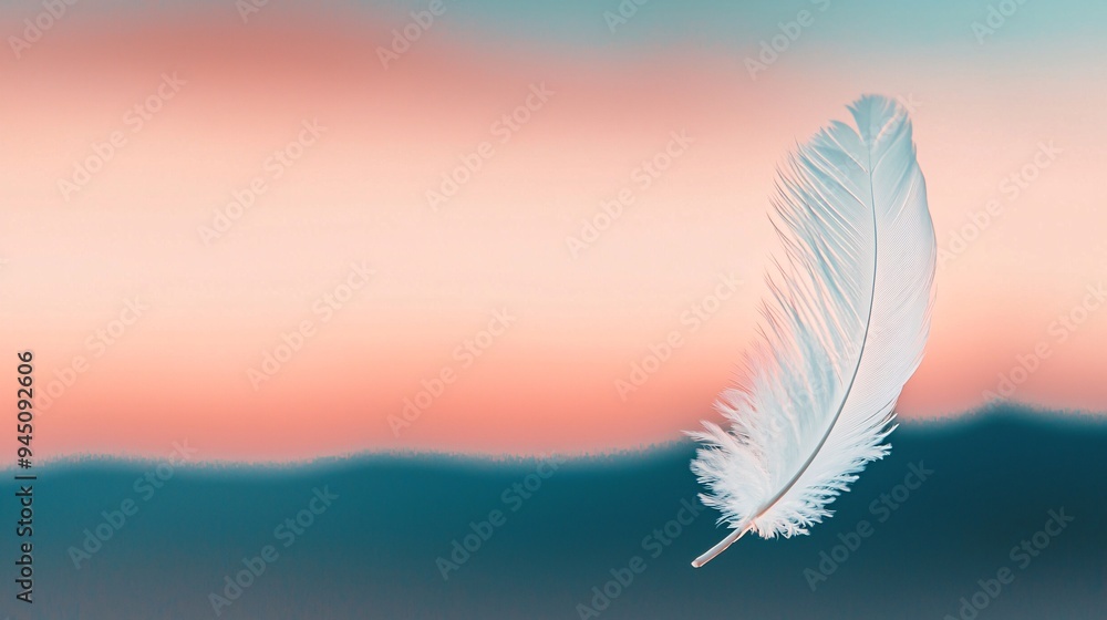 White feather floating in pastel sunset sky White feather floating in pastel sunset sky