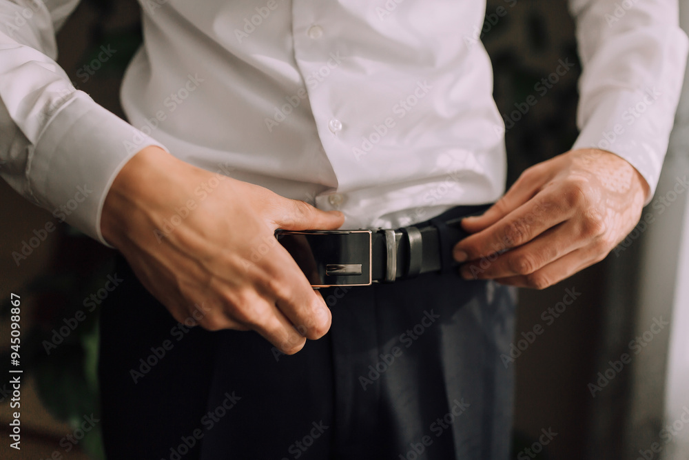 A man is adjusting his belt. Concept of formality and attention to detail A man is adjusting his belt. Concept of formality and attention to detail