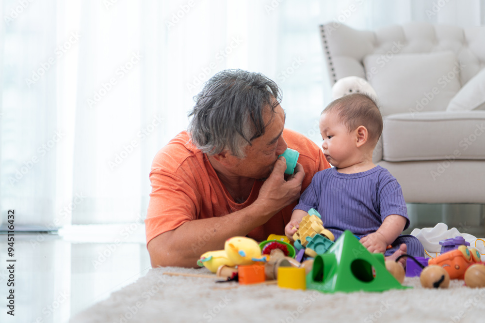 Grandfather and their little grandchild play happily in the living room of the house Grandfather and their little grandchild play happily in the living room of the house