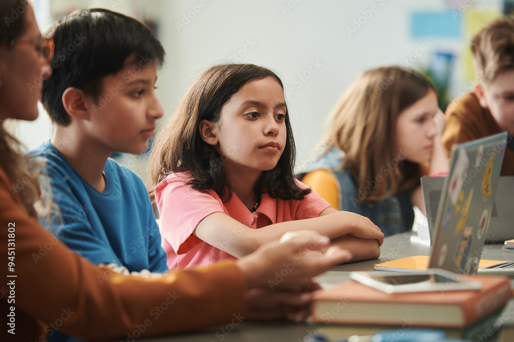 Portrait of cute young girl looking at computer screen with group of children in school classroom Portrait of cute young girl looking at computer screen with group of children in school classroom