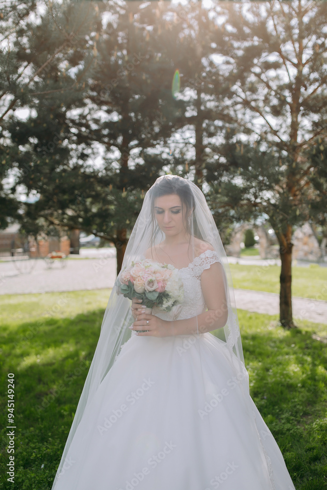 A woman in a white dress is standing in a field with a veil over her face. She is holding a bouquet of flowers A woman in a white dress is standing in a field with a veil over her face. She is holding a bouquet of flowers