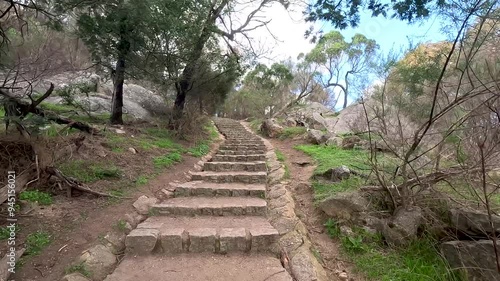 Walking perspective of a scenic hike through an Australian native forest, with stone stairs leading up a rugged path filled with rocks and boulders in You Yangs Regional Park near Melbourne Australia photo