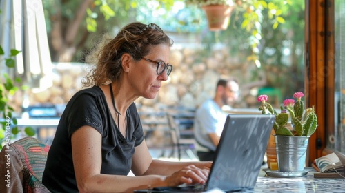 Israel relaxed woman in her 40s working on laptop at coffee place in city.