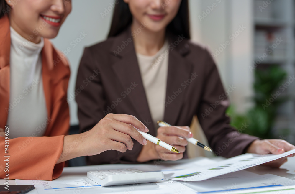 Team of Asian businesswomen analyze and brainstorm using calculators Financial data pointing hand on sheet. Graph chart showing income on laptop. Concept of teamwork process, growth. Team of Asian businesswomen analyze and brainstorm using calculators Financial data pointing hand on sheet. Graph chart showing income on laptop. Concept of teamwork process, growth.