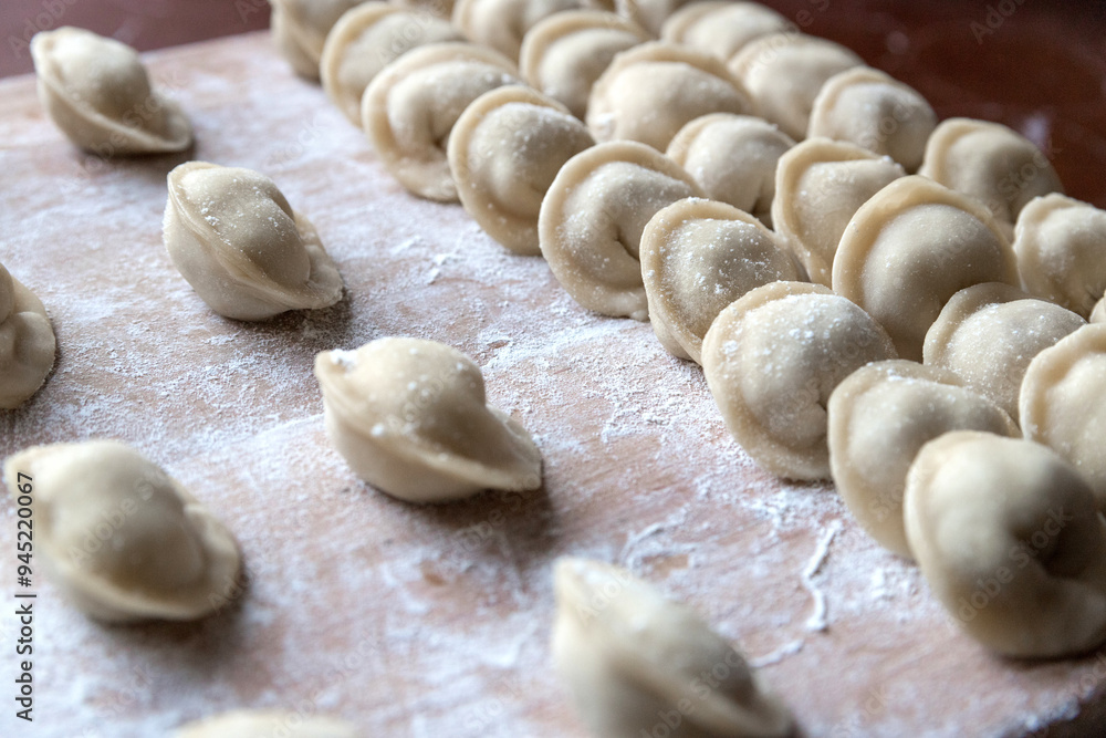 The raw dumplings were placed on a wooden cooking board, sprinkled with flour. The filling is minced meat, potatoes, cheese or cottage cheese. A semi-finished product, ready for cooking. The raw dumplings were placed on a wooden cooking board, sprinkled with flour. The filling is minced meat, potatoes, cheese or cottage cheese. A semi-finished product, ready for cooking.