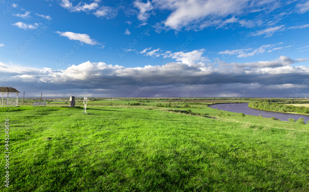 Obraz premium A large field of grass with a river running through it