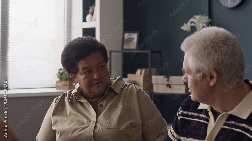 Waist up of multiracial old couple going through marriage breakdown sitting by their family psychologist at modern office and having argument Waist up of multiracial old couple going through marriage breakdown sitting by their family psychologist at modern office and having argument