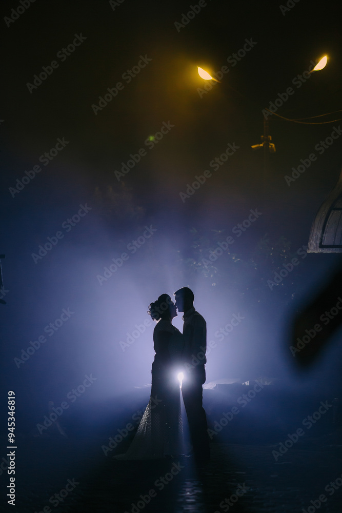 A couple is kissing in the rain, with the man holding a flashlight. The image has a romantic and intimate mood A couple is kissing in the rain, with the man holding a flashlight. The image has a romantic and intimate mood