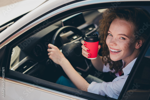 Photo of shiny attractive lady driver dressed white shirt smiling riding car enjoy coffee outdoors urban city street photo