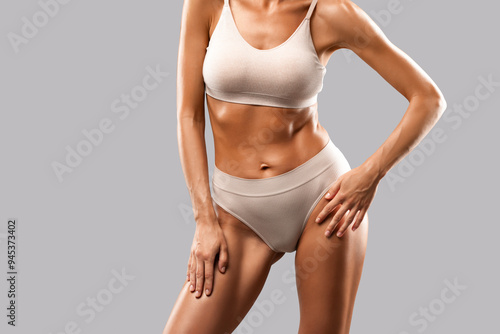 A slender swarthy woman in beige underwear on a isolated background. Healthy lifestyle, sport and diet.