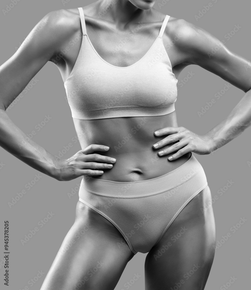 Fototapeta premium A slender swarthy woman in beige underwear on a isolated background. Healthy lifestyle, sport and diet.