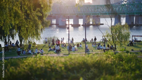 Vibrant Park Life by the Han River: People Relaxing, Gathering, and Enjoying Nature Near the Bridge at Sunset