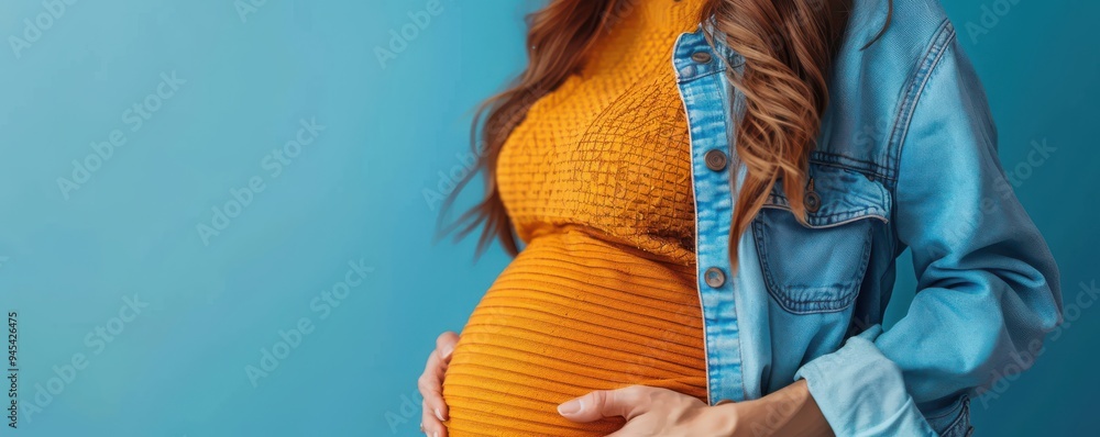 Fototapeta premium Pregnant woman in a flowing white dress holding her belly, symbolizing motherhood and new beginnings. Free copy space for banner.