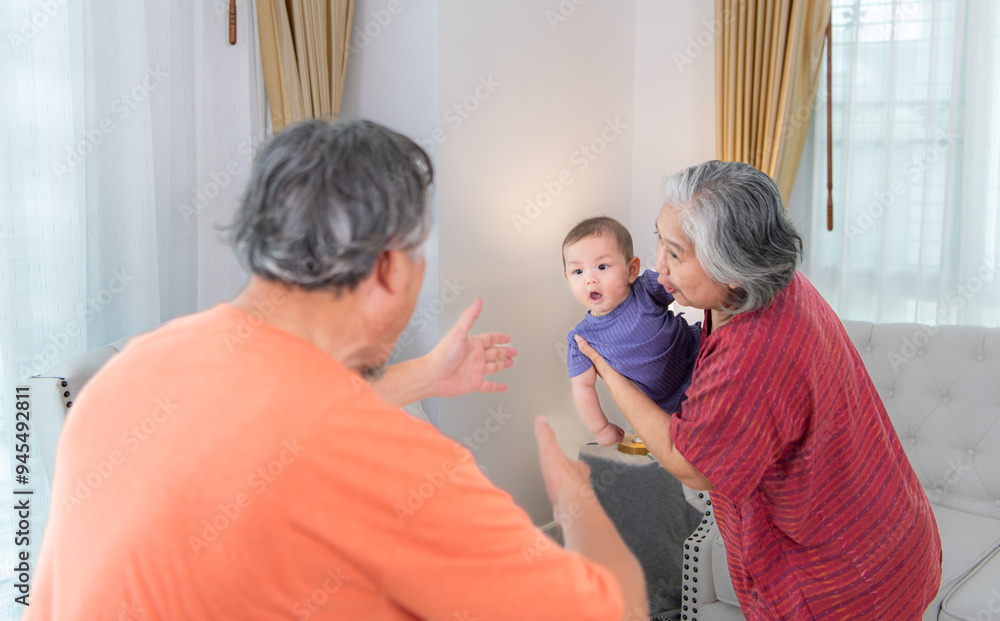 Obraz premium Grandparents and their little grandchild play happily in the living room of the house