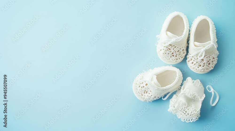 Top view of tiny white baby shoes with lace accents, carefully arranged on a smooth, light blue background, exuding elegance and simplicity. Top view of tiny white baby shoes with lace accents, carefully arranged on a smooth, light blue background, exuding elegance and simplicity.