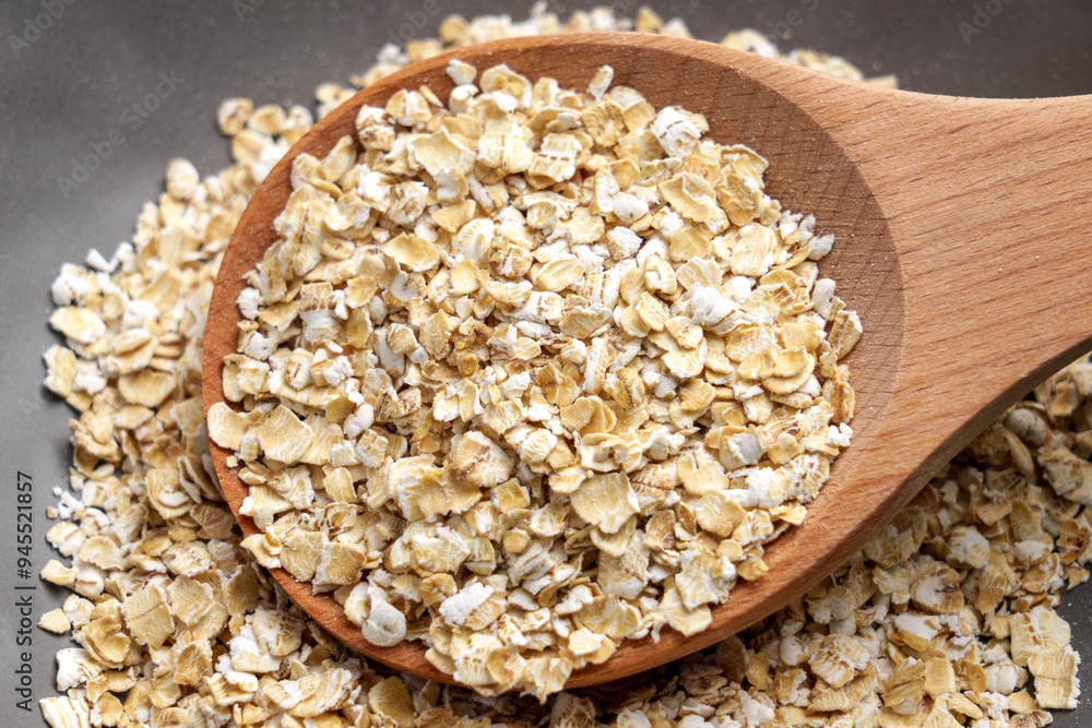 Fresh rolled oat flakes in wooden spoon close up. Uncooked organic oatmeal porridge. Morning breakfast gluten free ingredients Fresh rolled oat flakes in wooden spoon close up. Uncooked organic oatmeal porridge. Morning breakfast gluten free ingredients