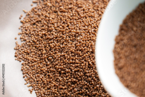 Preparation of dry buckwheat couscous. Nutritious raw ingredient in gray kitchen bowl and white cup for steaming close up