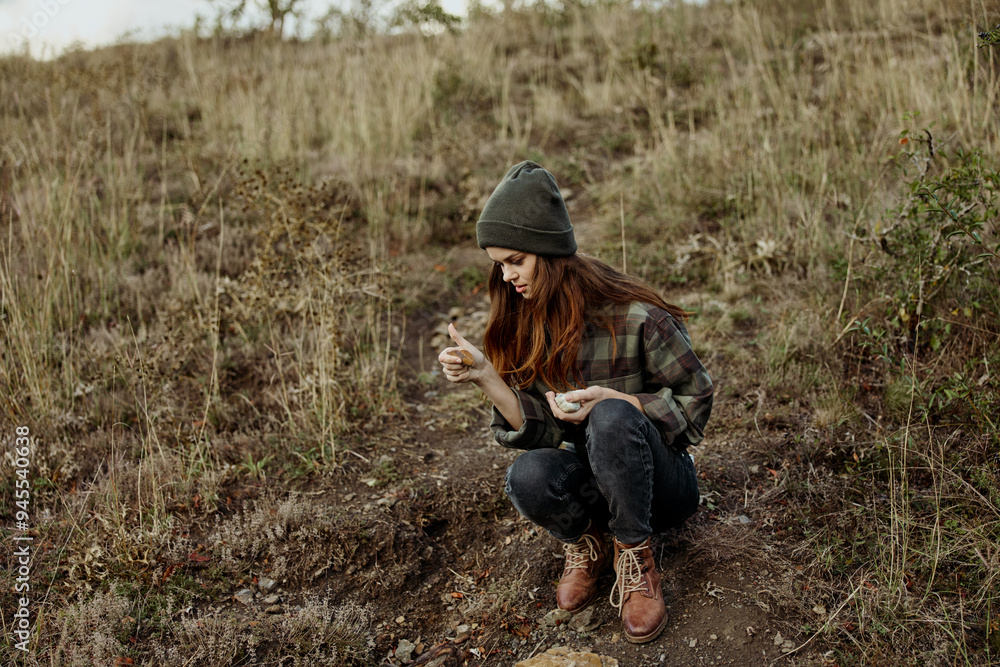 Fototapeta premium A stylish woman wearing a beanie and plaid shirt enjoying the breathtaking view from the hilltop during a leisure trip