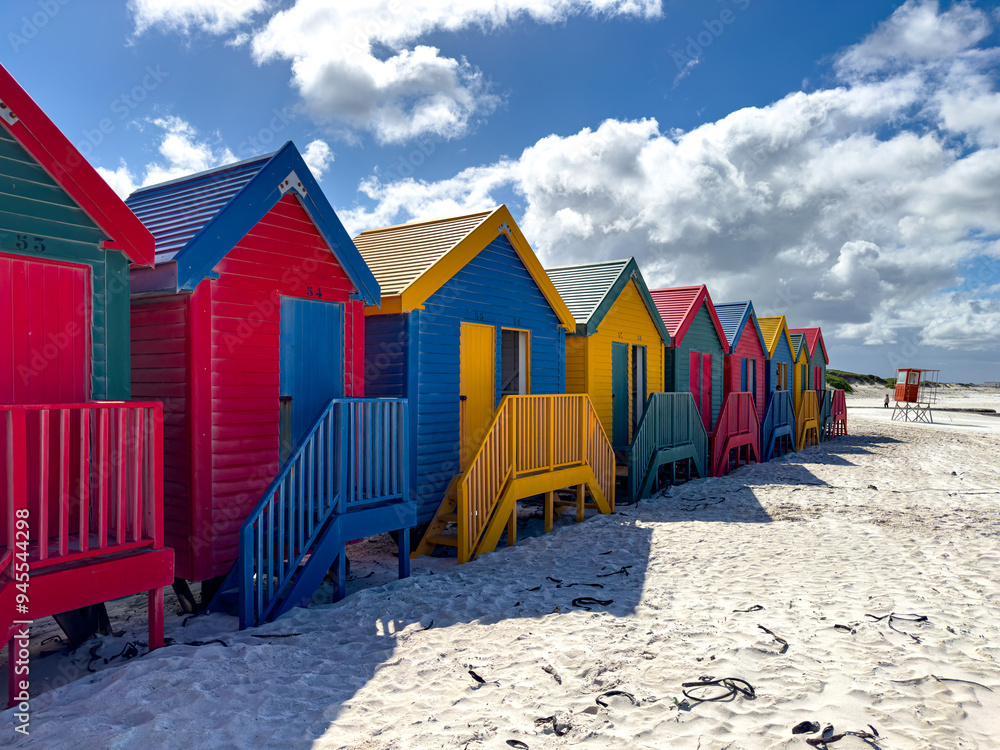 Naklejka premium The iconic Muizenberg Beach huts for people to change in and out of bathing suits situated on Muizenberg Beach, Cape Town, South Africa