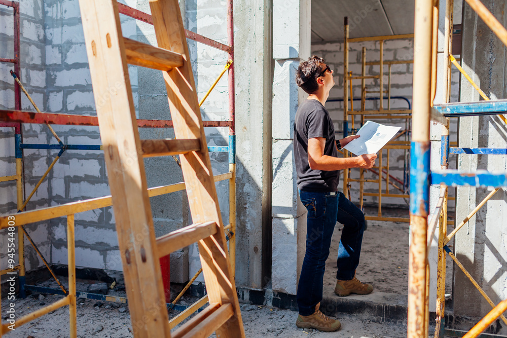 Man architect engineer checking house under construction comparing with blueprint plan on paper. Gas block Man architect engineer checking house under construction comparing with blueprint plan on paper. Gas block