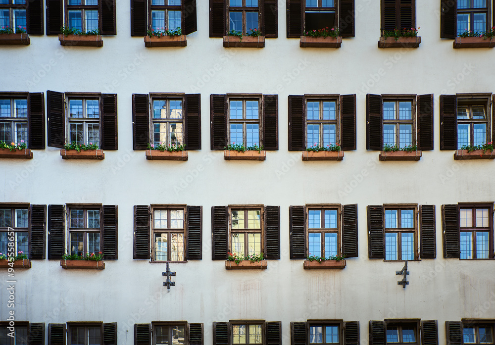 Old building facade with pattern of open old windows with wooden jalousie and flowers in Innsbruck. Historical architecture or medieval exterior with opened timbered blinds or louver. Austria Old building facade with pattern of open old windows with wooden jalousie and flowers in Innsbruck. Historical architecture or medieval exterior with opened timbered blinds or louver. Austria