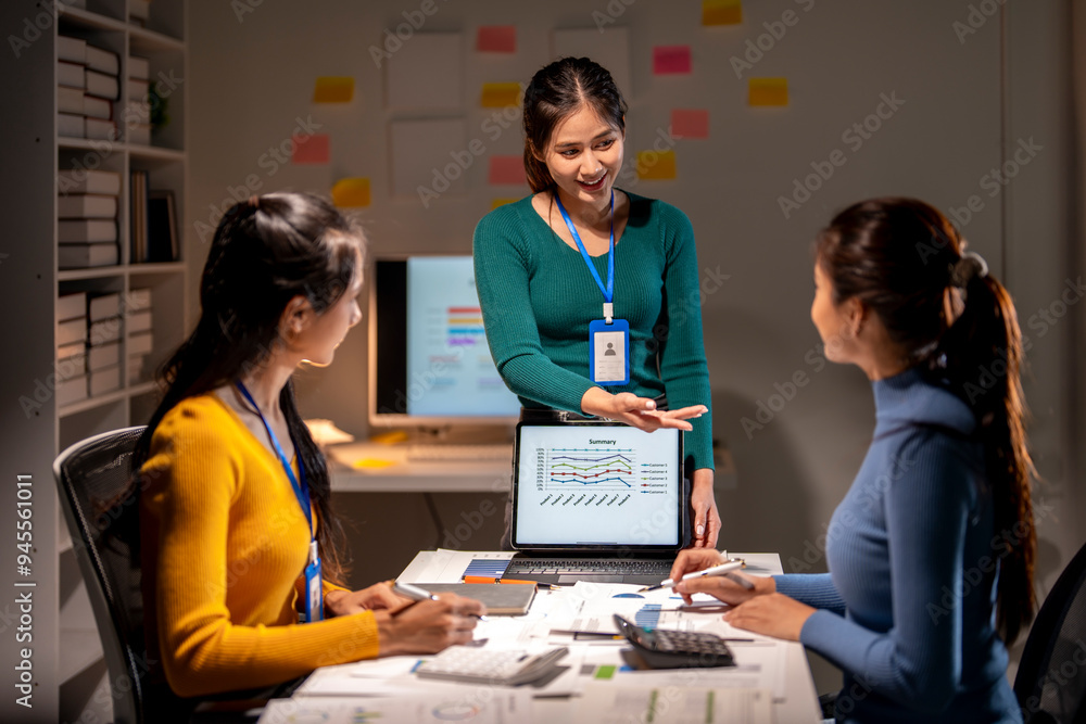 Three women are sitting at a table with a laptop open in front of them Three women are sitting at a table with a laptop open in front of them