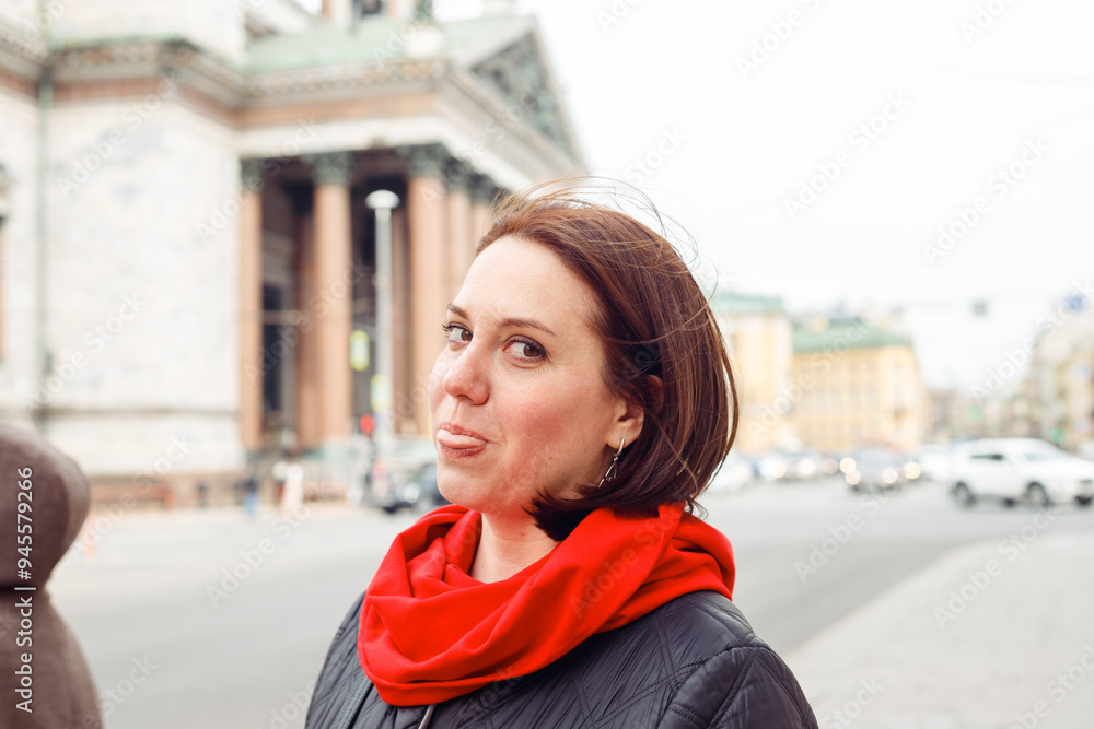 Fototapeta premium caucasian female woman playfully sticks out tongue on street of european historical city. date, flirt, love. female portrait