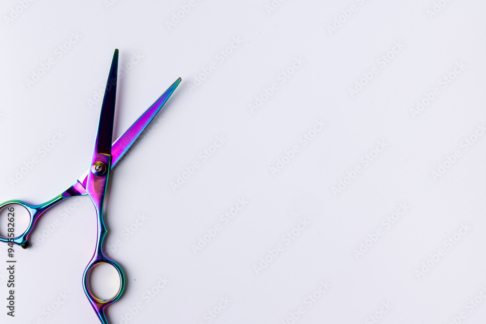 Close-up view of open scissors on a white surface, seen from above. The scissors are aligned to the left Close-up view of open scissors on a white surface, seen from above. The scissors are aligned to the left