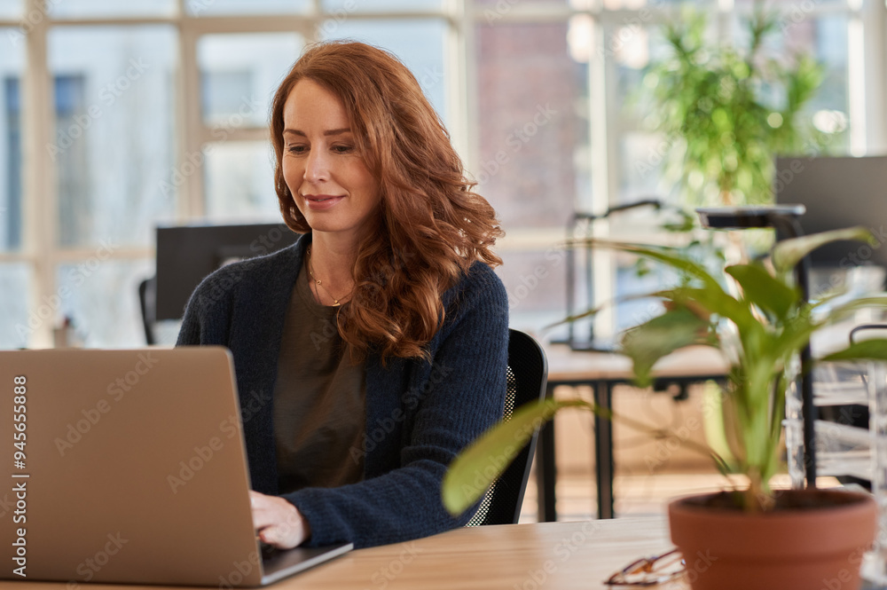 Smiling businesswoman working on a laptop at her office desk Smiling businesswoman working on a laptop at her office desk