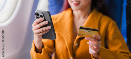 Fotografia In-Flight Shopping Spree: Woman in yellow using phone and credit card on airplan