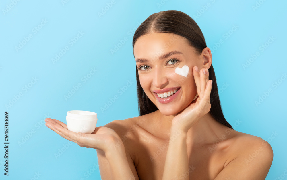 Happy lady holding jar and applying moisturizing cream, enjoy new skin hydration product, posing over blue background and smiling Happy lady holding jar and applying moisturizing cream, enjoy new skin hydration product, posing over blue background and smiling