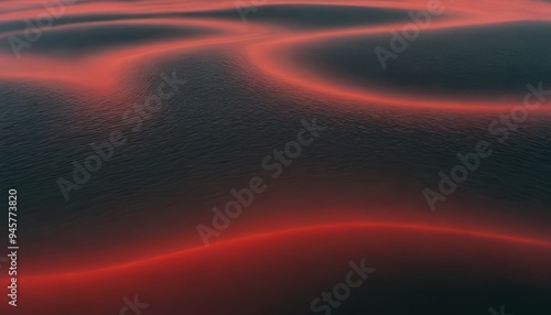 Red and black sand dunes in the desert at sunset.