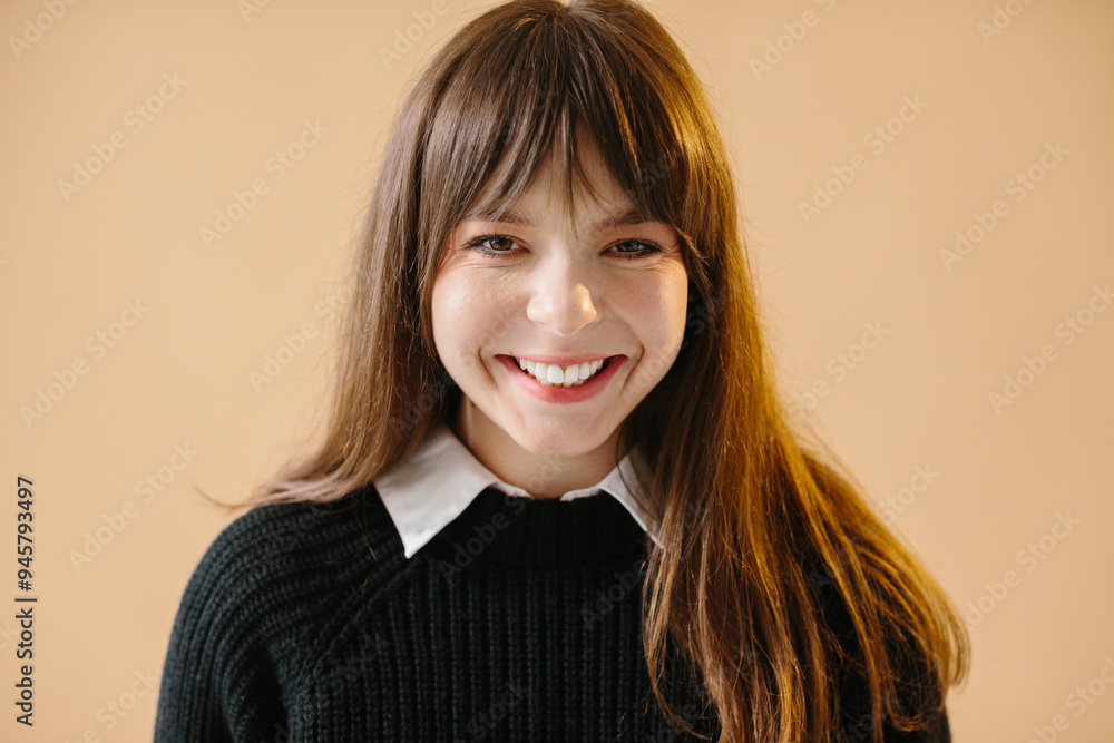 Portrait of young smiling brunette woman isolated on beige background, looking at camera. Portrait of young smiling brunette woman isolated on beige background, looking at camera.