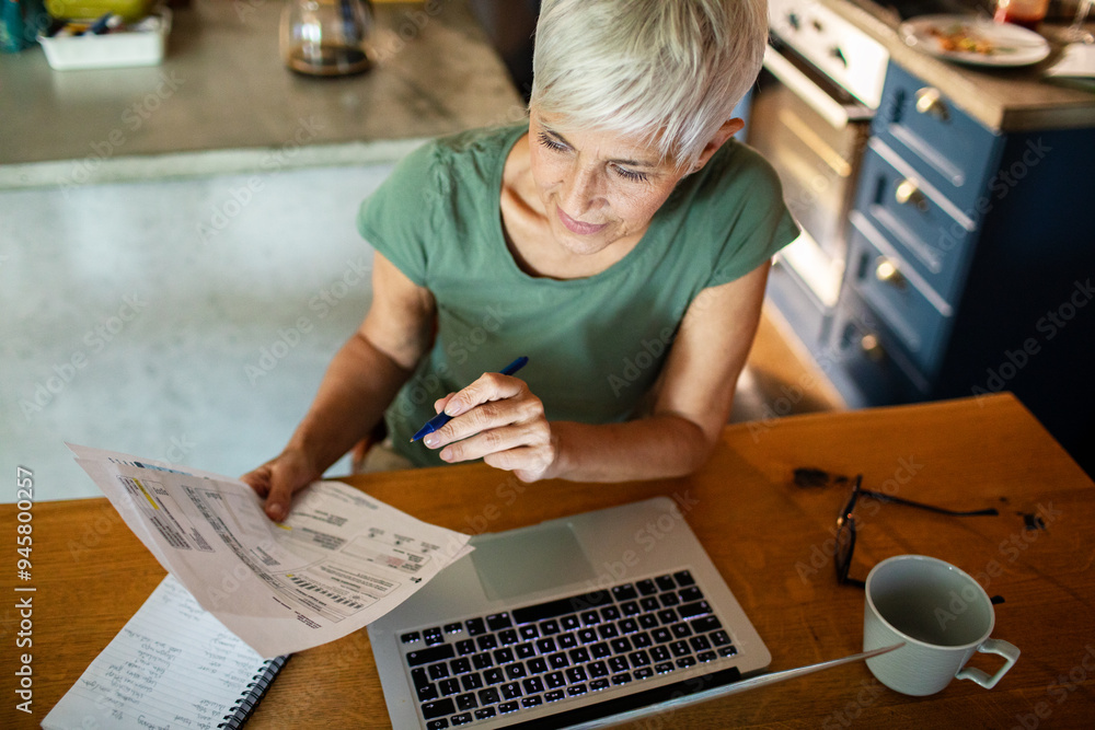 Senior woman managing bills and finances online at home Senior woman managing bills and finances online at home