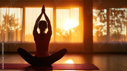 Yoga enthusiast practicing seated meditation in a serene studio with sunrise backdrop, promoting wellness and inner peace.