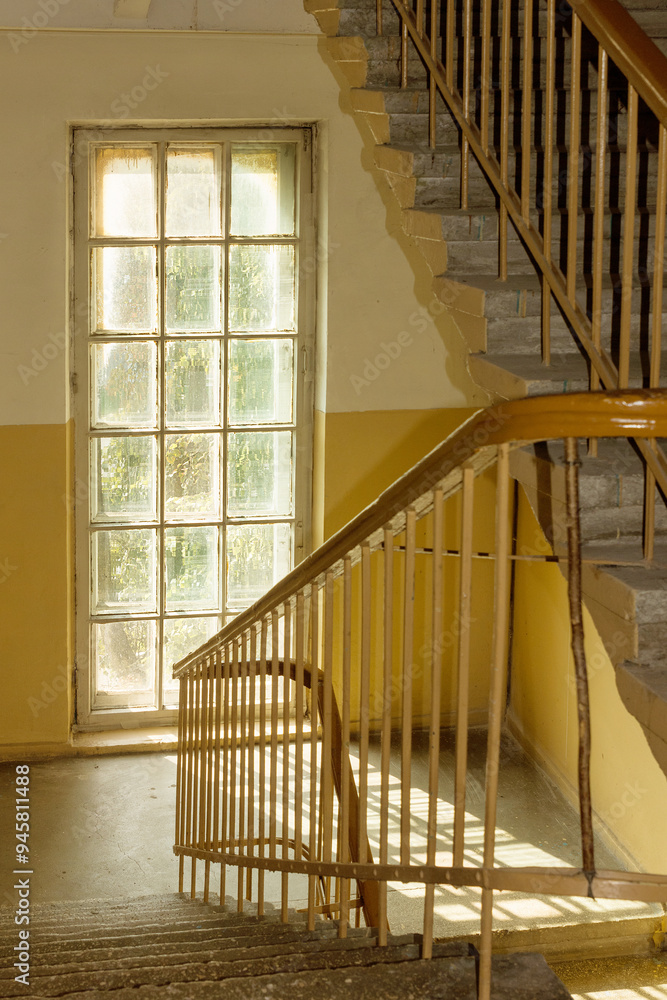 Obraz premium Staircase and window illuminated by the sun in the old entrance of an old house.