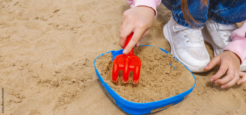 A child girl playing in the sandbox at the playground outdoors. Little girl playing with sand molds and making mud pies. Outdoor creative activities for kids. A child girl playing in the sandbox at the playground outdoors. Little girl playing with sand molds and making mud pies. Outdoor creative activities for kids.