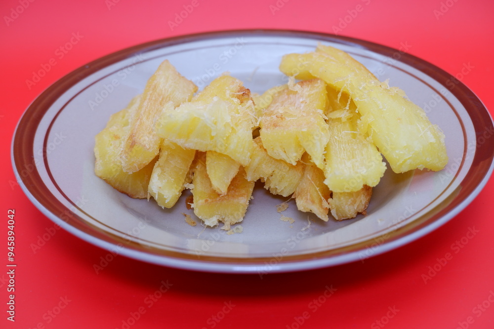 Fried cassava served on a plate. Fried cassava dish isolated on a red background. Fried cassava served on a plate. Fried cassava dish isolated on a red background.
